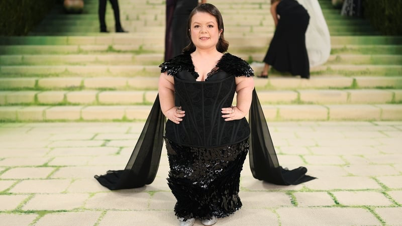 Ativista Sinead Burke posa para foto nas escadas do Met Gala usando um vestido preto